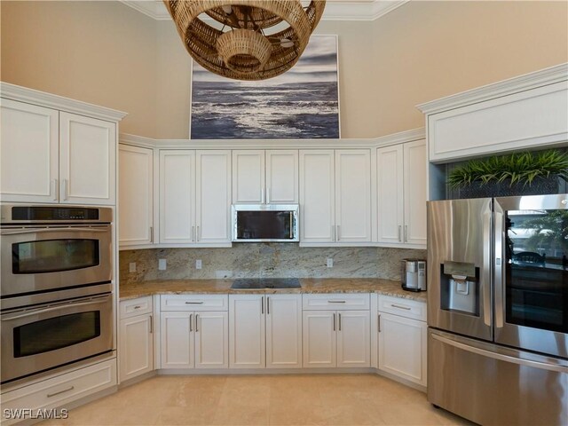 kitchen featuring stainless steel appliances, white cabinets, ornamental molding, decorative backsplash, and light stone countertops