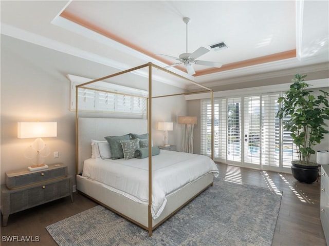 bedroom with ceiling fan, dark hardwood / wood-style flooring, a raised ceiling, and crown molding