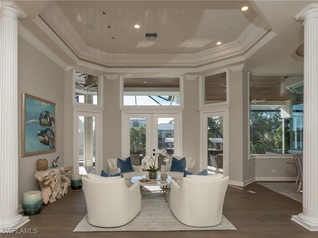 sunroom / solarium featuring crown molding, dark hardwood / wood-style floors, a tray ceiling, and decorative columns