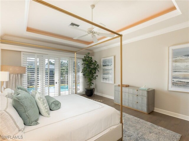 bedroom featuring ornamental molding, ceiling fan, a tray ceiling, and dark hardwood / wood-style flooring