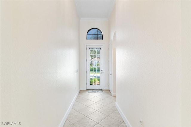 doorway to outside featuring light tile patterned floors, a towering ceiling, and crown molding