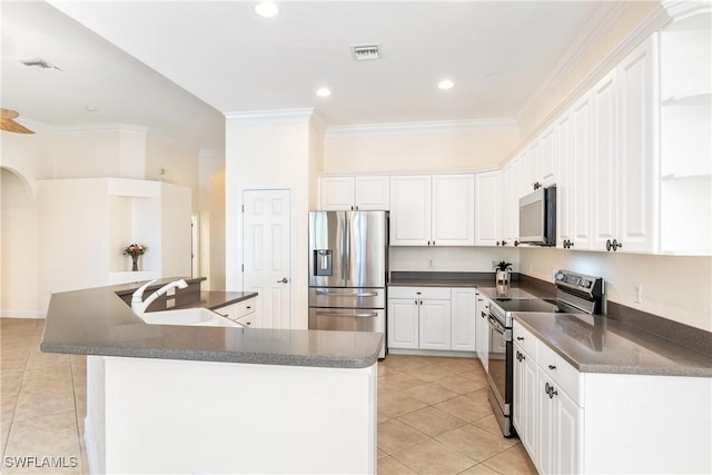 kitchen with sink, stainless steel appliances, light tile patterned floors, a kitchen island, and white cabinets