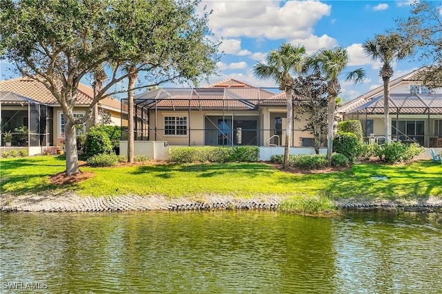 rear view of house with a lanai, a yard, and a water view