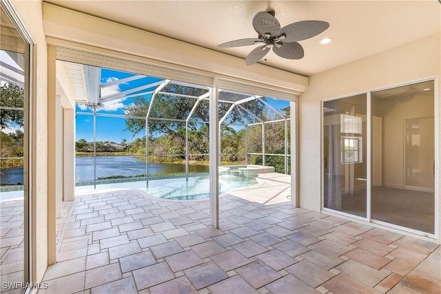 unfurnished sunroom with ceiling fan, a swimming pool, and a water view