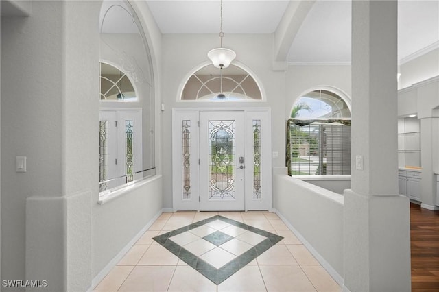 tiled entryway featuring crown molding and a healthy amount of sunlight