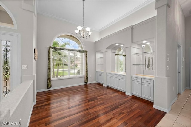 unfurnished dining area featuring a chandelier, dark tile patterned floors, and ornamental molding