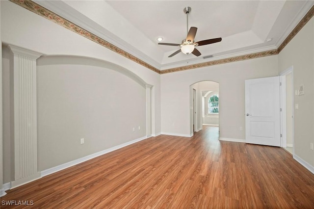 unfurnished room featuring hardwood / wood-style floors, a raised ceiling, ceiling fan, and crown molding