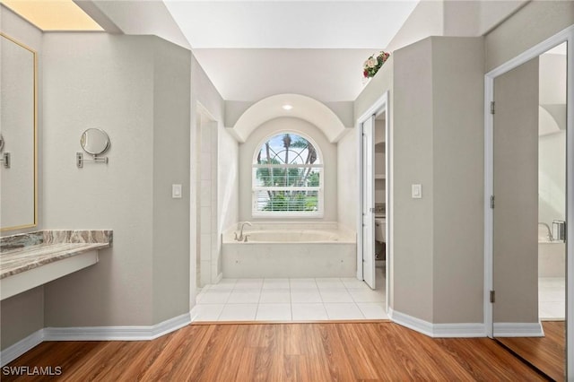 bathroom featuring a bathing tub, toilet, wood-type flooring, and vaulted ceiling