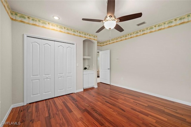 unfurnished bedroom with dark hardwood / wood-style flooring, a closet, and ceiling fan