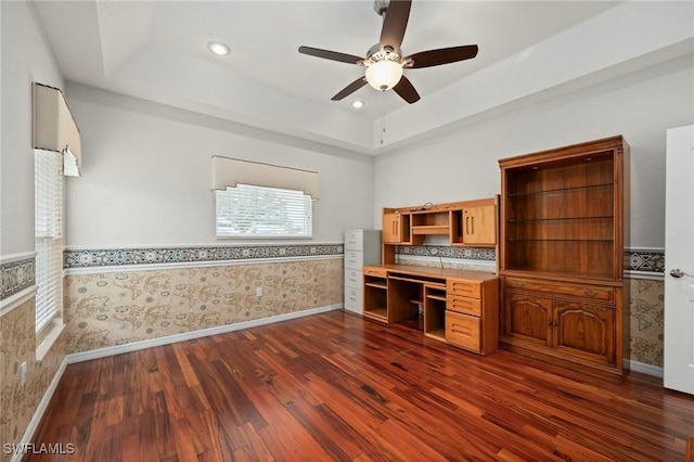 kitchen featuring a tray ceiling, ceiling fan, dark wood-type flooring, and built in desk