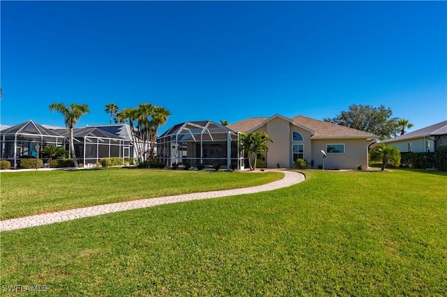 rear view of property featuring a lawn and glass enclosure