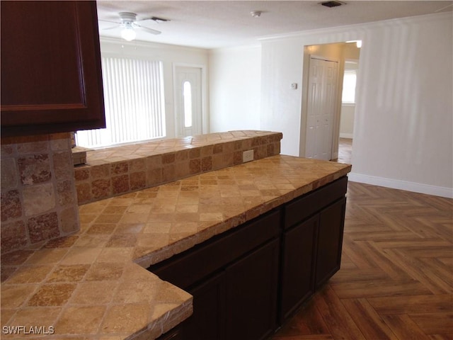 kitchen with ceiling fan, dark brown cabinetry, and parquet flooring