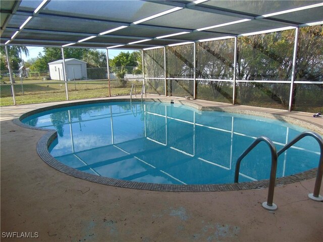 view of swimming pool featuring a yard, a storage shed, and a lanai