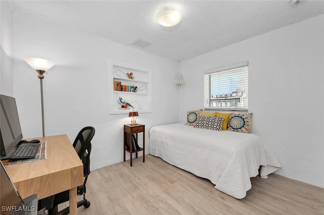 bedroom with light hardwood / wood-style floors and a textured ceiling