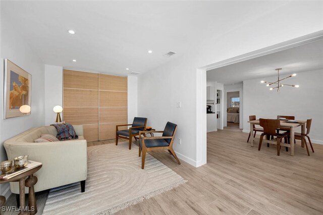 living room with light hardwood / wood-style floors and a notable chandelier