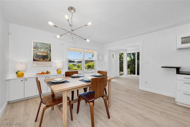 dining space with light hardwood / wood-style floors and an inviting chandelier