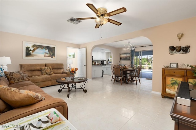 tiled living room featuring ceiling fan with notable chandelier