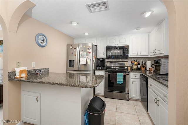 kitchen with light tile patterned floors, kitchen peninsula, dark stone counters, white cabinets, and black appliances