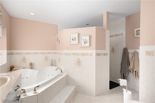 bathroom with tile patterned flooring, a relaxing tiled tub, and tile walls