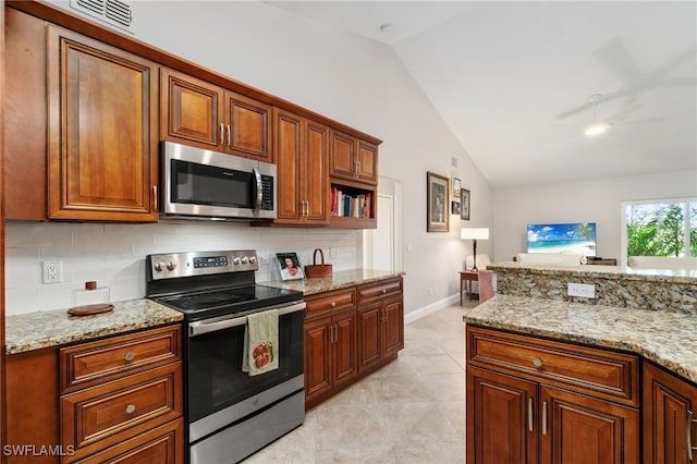 kitchen featuring vaulted ceiling, light stone counters, appliances with stainless steel finishes, and backsplash