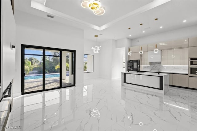 kitchen featuring hanging light fixtures, decorative backsplash, double oven, a tray ceiling, and white cabinetry