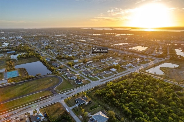 aerial view at dusk featuring a water view