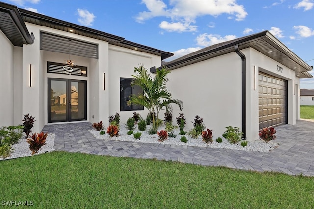 doorway to property featuring a lawn, a garage, and french doors