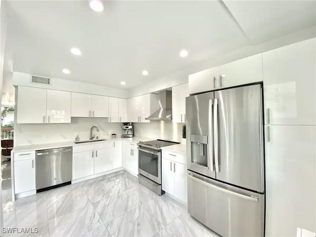 kitchen featuring white cabinets, appliances with stainless steel finishes, sink, and wall chimney range hood