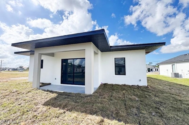 back of house with central AC unit and a yard