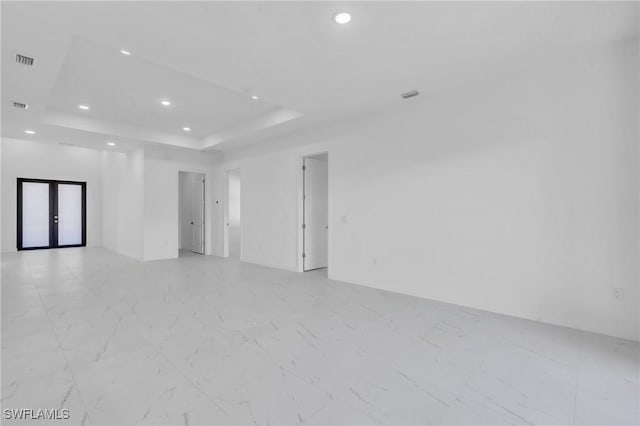 spare room featuring french doors and a raised ceiling