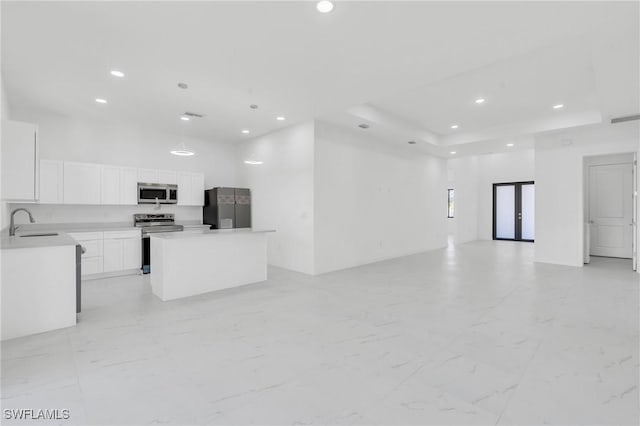 kitchen with sink, a center island, appliances with stainless steel finishes, a raised ceiling, and white cabinets