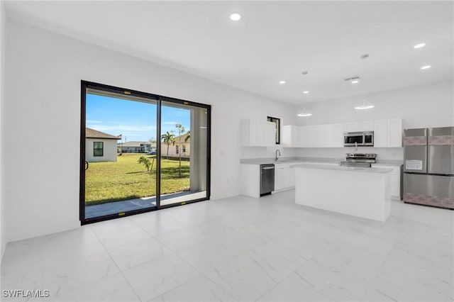 kitchen featuring appliances with stainless steel finishes, sink, white cabinets, a center island, and light stone countertops