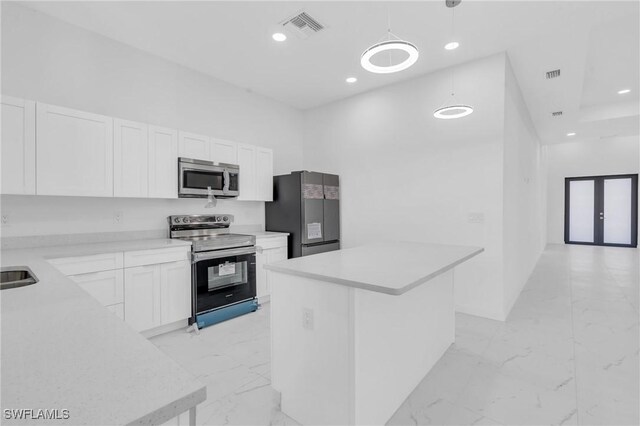 kitchen featuring stainless steel appliances, white cabinetry, a kitchen island, and hanging light fixtures