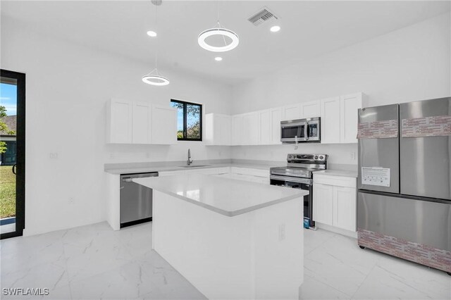 kitchen featuring a kitchen island, white cabinetry, appliances with stainless steel finishes, and pendant lighting