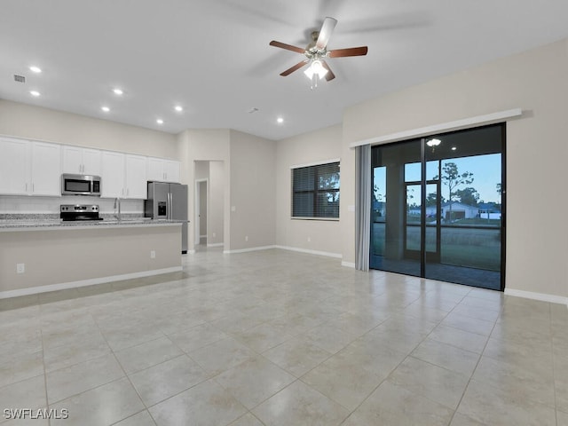 interior space featuring white cabinets, ceiling fan, light tile patterned floors, light stone countertops, and appliances with stainless steel finishes