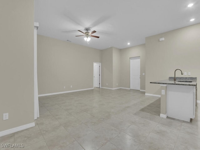 unfurnished living room featuring ceiling fan and sink