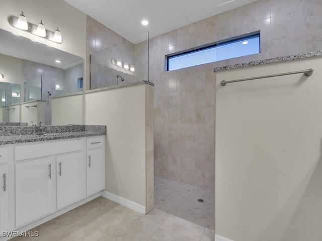 bathroom with tile patterned flooring, vanity, and a tile shower