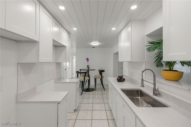 kitchen featuring backsplash, white cabinetry, sink, and light tile patterned floors