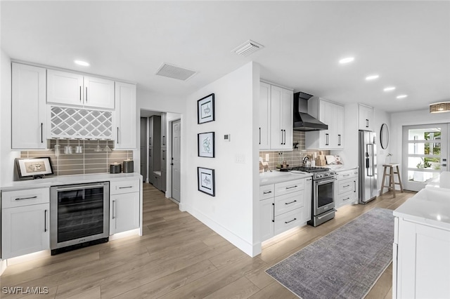 kitchen featuring tasteful backsplash, wall chimney exhaust hood, high quality appliances, white cabinets, and wine cooler