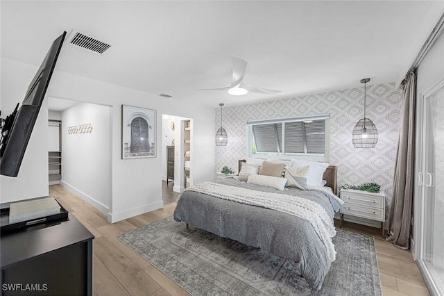 bedroom with ceiling fan, ensuite bath, and light hardwood / wood-style flooring