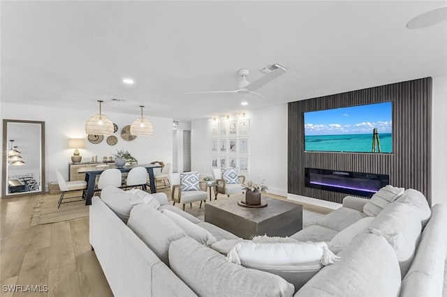 living room featuring ceiling fan, a fireplace, and light hardwood / wood-style flooring