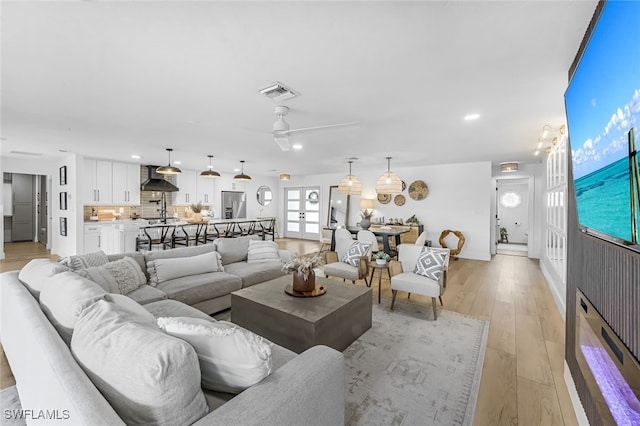 living room featuring ceiling fan, french doors, and light wood-type flooring