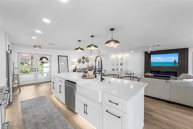 kitchen with white cabinetry, sink, an island with sink, pendant lighting, and appliances with stainless steel finishes