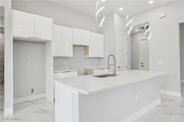 kitchen featuring white cabinets, sink, and an island with sink