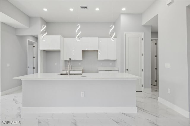 kitchen with white cabinets, sink, an island with sink, and hanging light fixtures