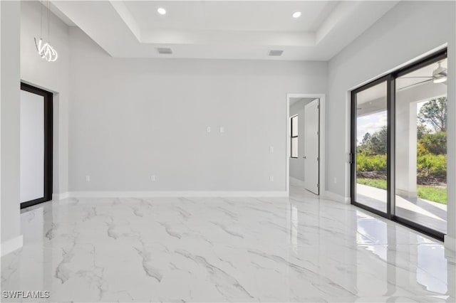 empty room featuring a tray ceiling and ceiling fan