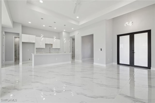 unfurnished living room featuring french doors, an inviting chandelier, a high ceiling, and sink