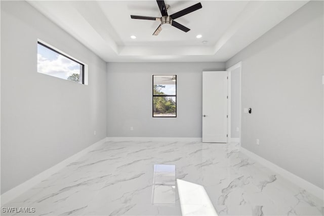 unfurnished room featuring ceiling fan and a raised ceiling