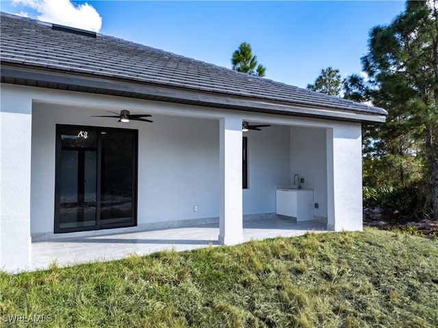 rear view of property featuring ceiling fan and a patio area