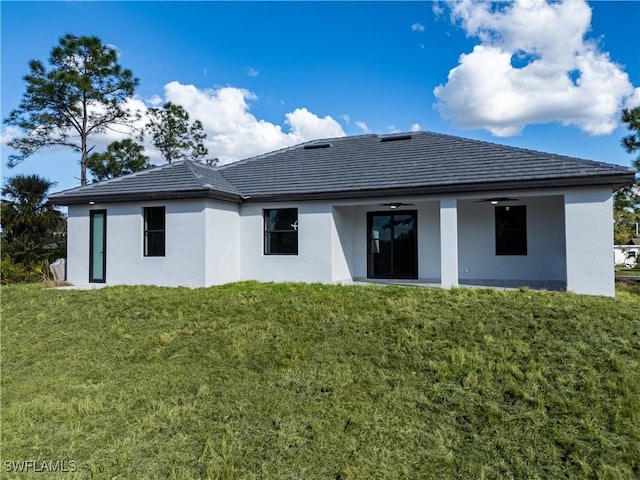 back of house with ceiling fan and a lawn